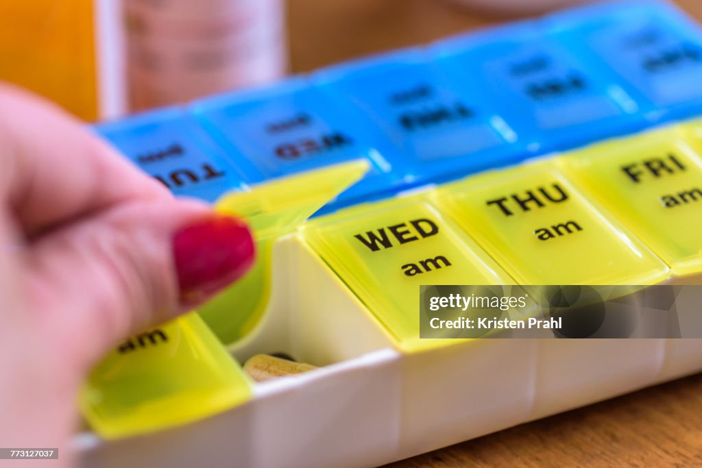 Cropped Hand Of Woman Taking Pills In Container With Text On Table