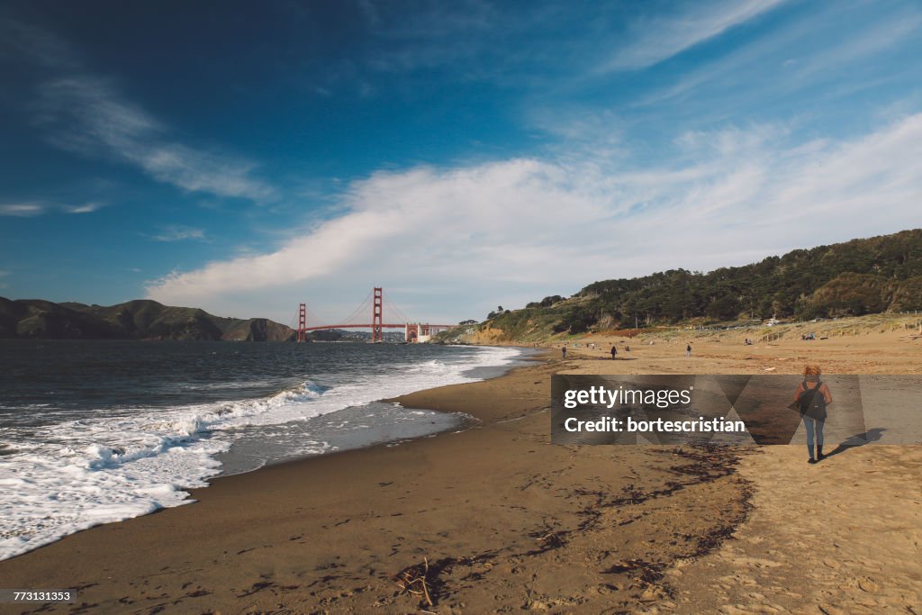 Vista trasera de una mujer adulta mediana con mochila caminando en la playa