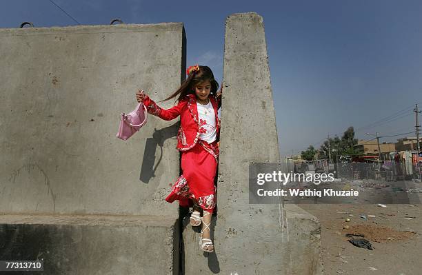 An Iraqi girl gets out of a concrete wall that surrounds a play ground on the first day of Eid al-Fitr on October 13, 2007 in the Shiite Sadr city...