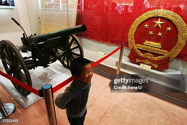 Boy stands in front of the salvo used on the founding ceremony on display ahead of the 17th Communist Party Congress at China Military Museum on...