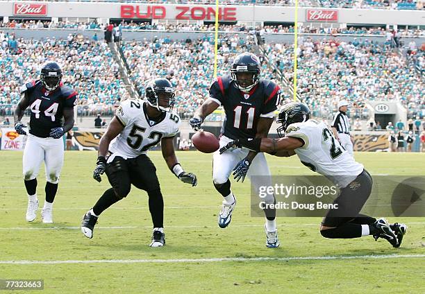 Wide receiver Andre Davis of the Houston Texans fumbles into the endzone as he is hit by Sammy Knight and linebacker Daryl Smith of the Jacksonville...
