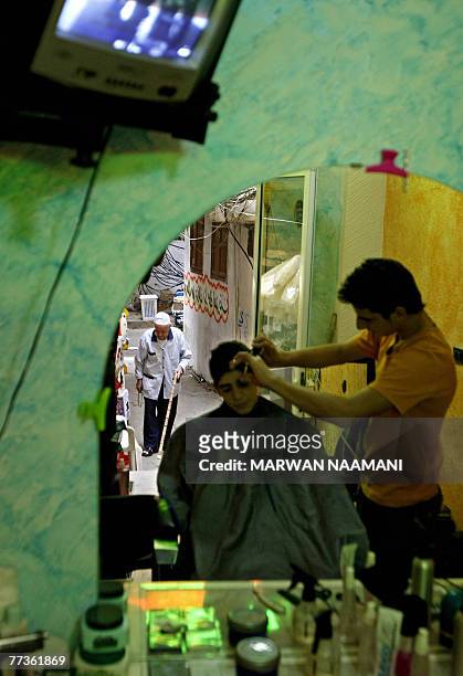 An elderly Palestinian refugee is reflected in the mirror of a barber shop as he walks down a cramped alley in the refugee camp of Burj al-Barajneh...