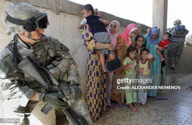 Staff Sergeant Fuller of Alpha Company, 1/38 Infantry Regiment, looks toward Iraqi women and children as he secures an area during a mopping-up...