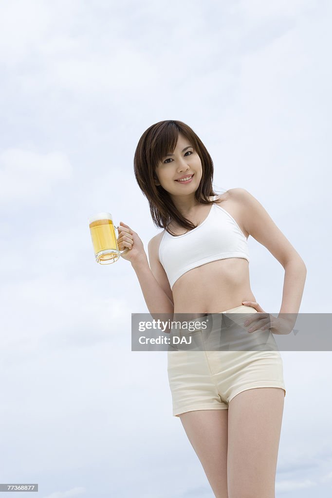 Young woman holding a beer glass, low angle view