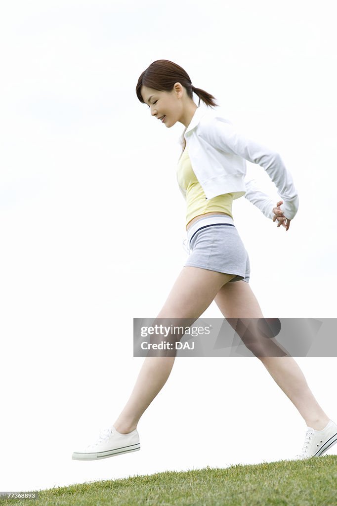 Young Woman walking on lawn, low angle view