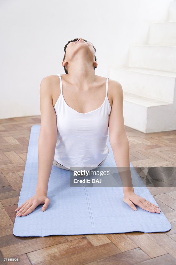 Young woman doing yoga exercise, stretching, front view  