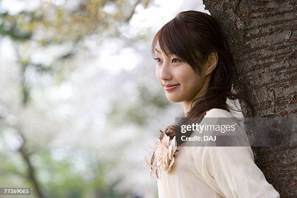 young woman leaning on wood, differential focus, side view - corsage imagens e fotografias de stock