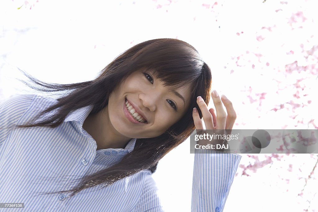 Portrait of a woman standing under the cherry tree, smiling and looking at camera, low angle view, white background, Japan