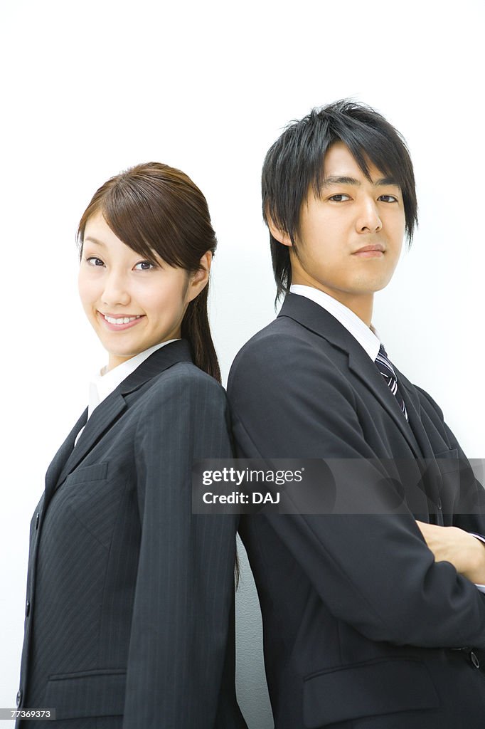 Businessman And Businesswoman Standing Back To Back, Side View, Waist Up,