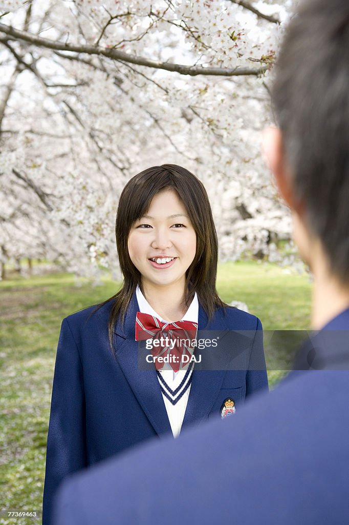 High School Student Girl Talking in Field with Cherry Blossom in the Background, Differential Focus