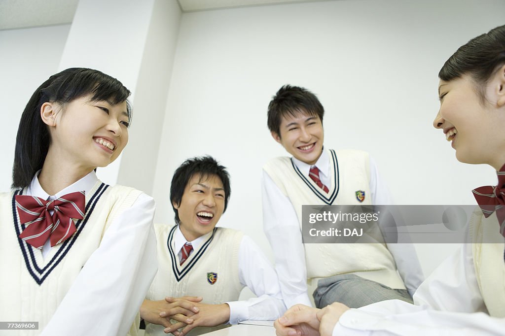 High school students sitting at desk and talking in classroom