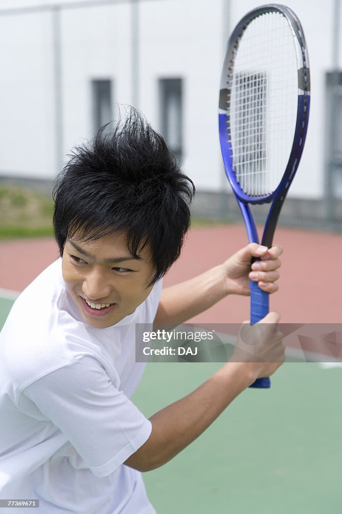 Teenage boy smiling and holding tennis racket