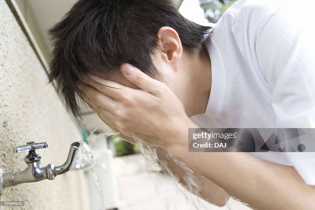 Teenage boy in gym cloth washing face, blurred motion