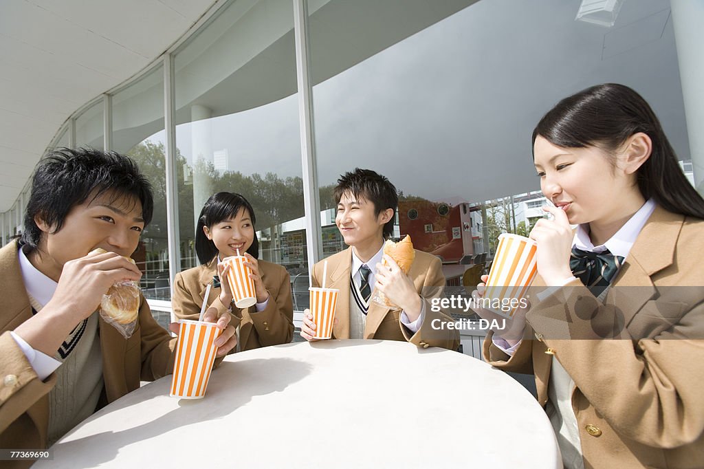 High school students having lunch at terrace, smiling