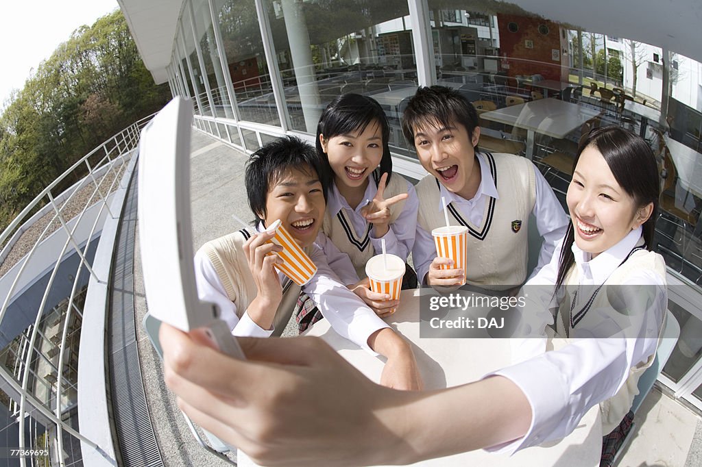High school students smiling and photographing with mobile phone, fish-eye lens