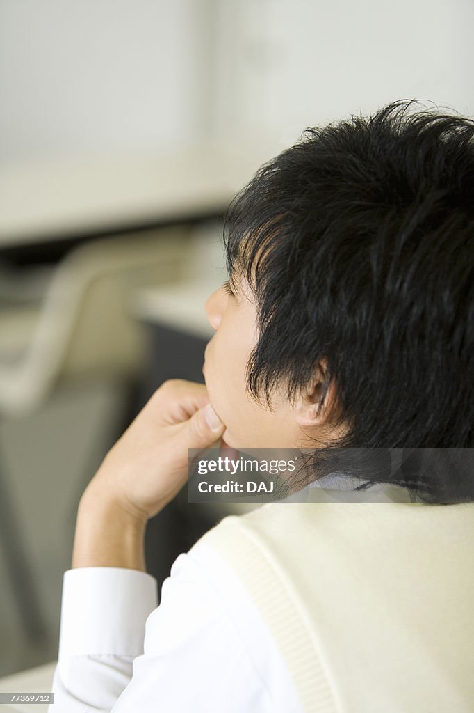 Teenage boy sitting at desk in classroom