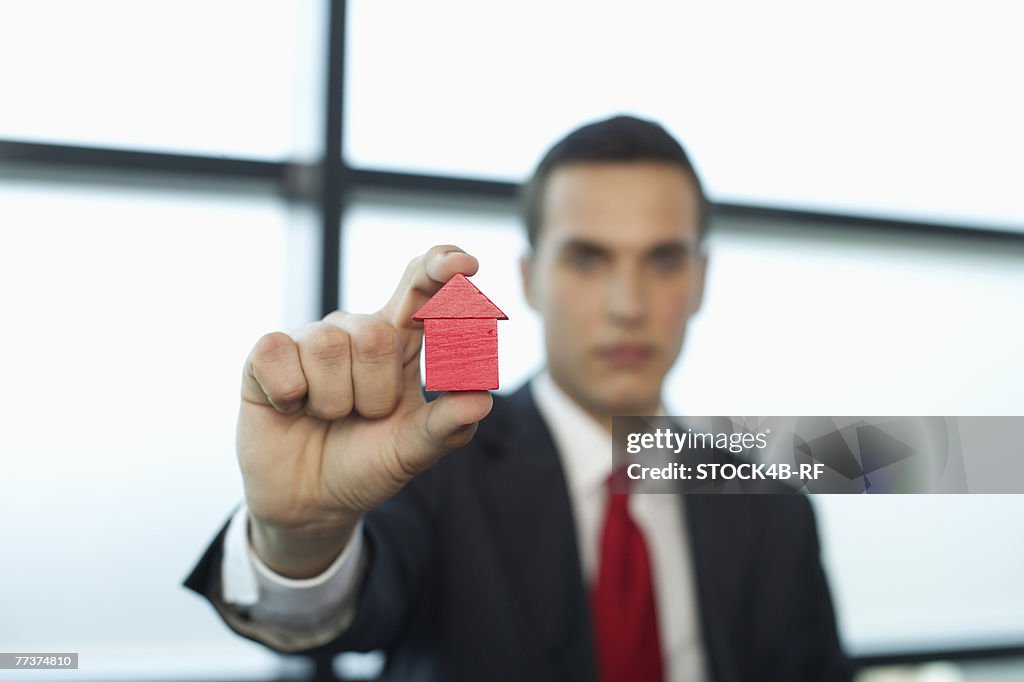 Businessman holding a model house between fingers