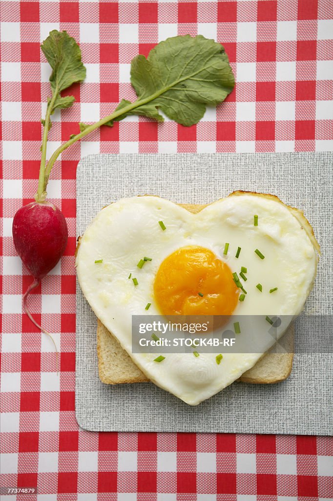 Heart-shaped fried egg on toast and radish