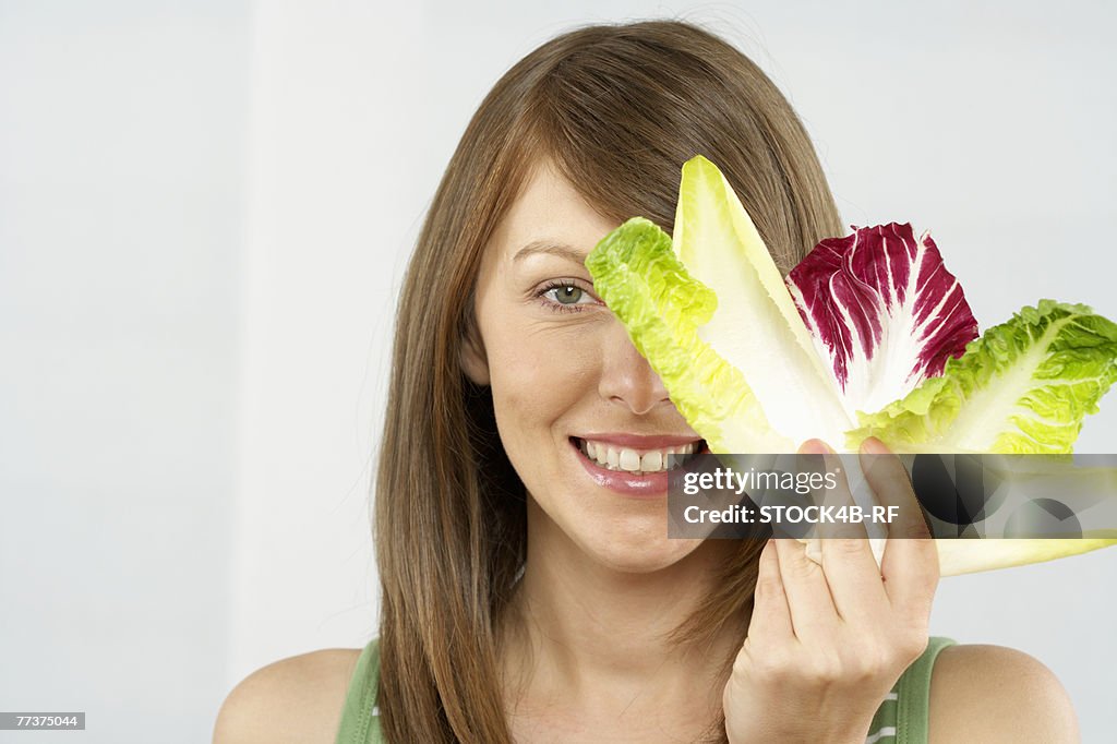 Mid adult woman holding several lettuce leafs in hand