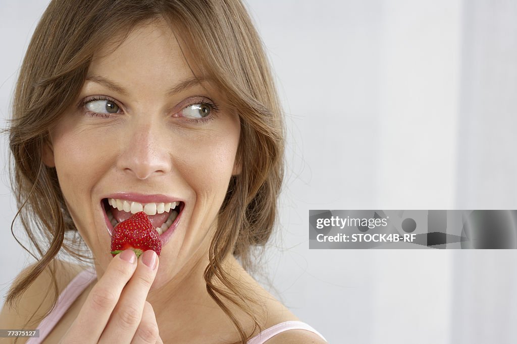 Mid adult woman eating a strawberry