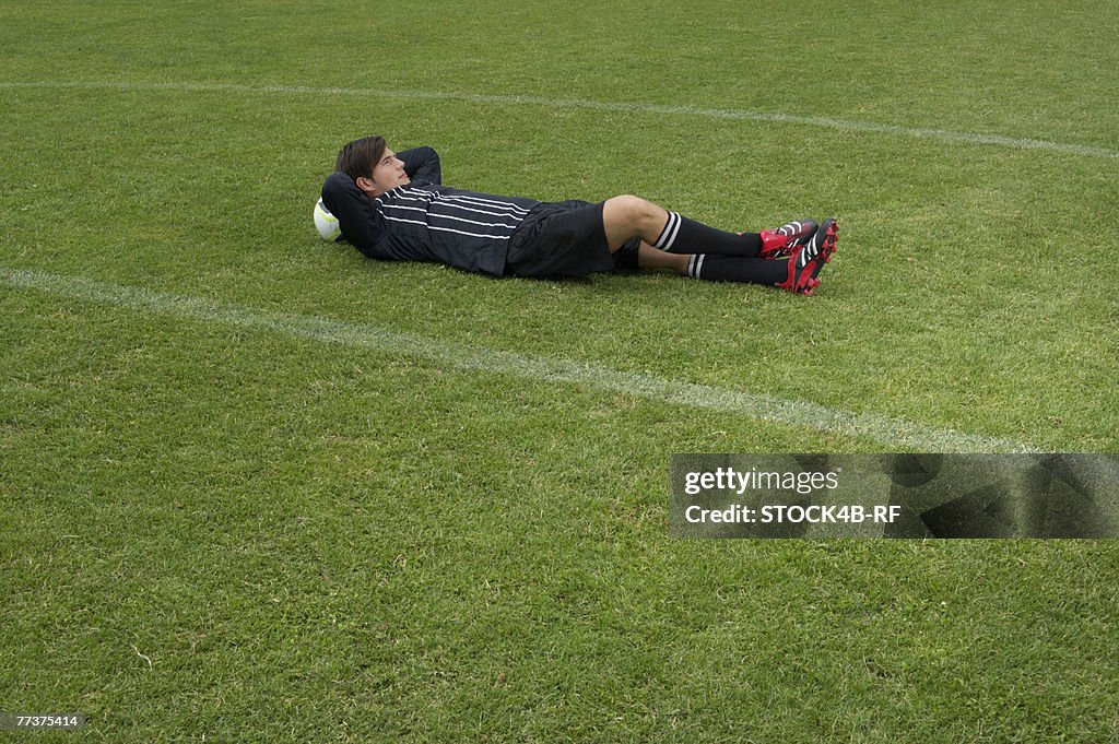 Relaxed referee lying on soccer field