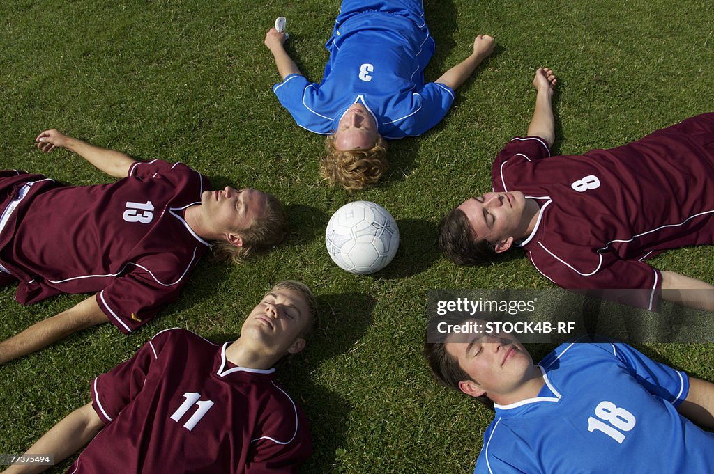 Kickers lying with closed eyes on soccer field