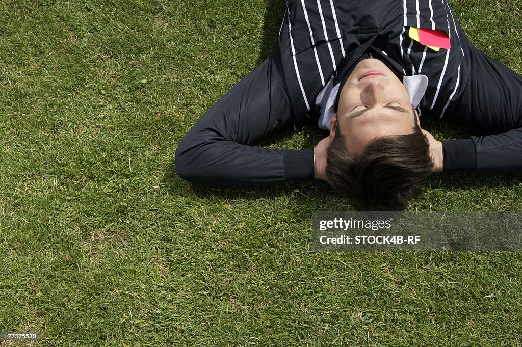 Relaxed referee lying on soccer field