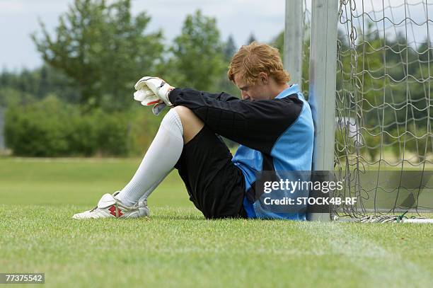 disappointed goalkeeper leaning against goal sitting on ground - bad goalkeeper stock pictures, royalty-free photos & images