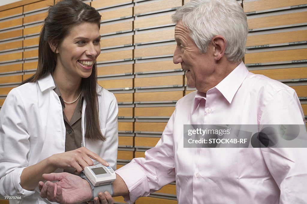 Female pharmacist taking customer's blood pressure 