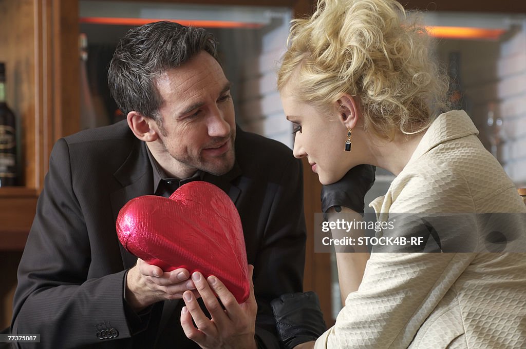 Man giving young woman a chocolate heart