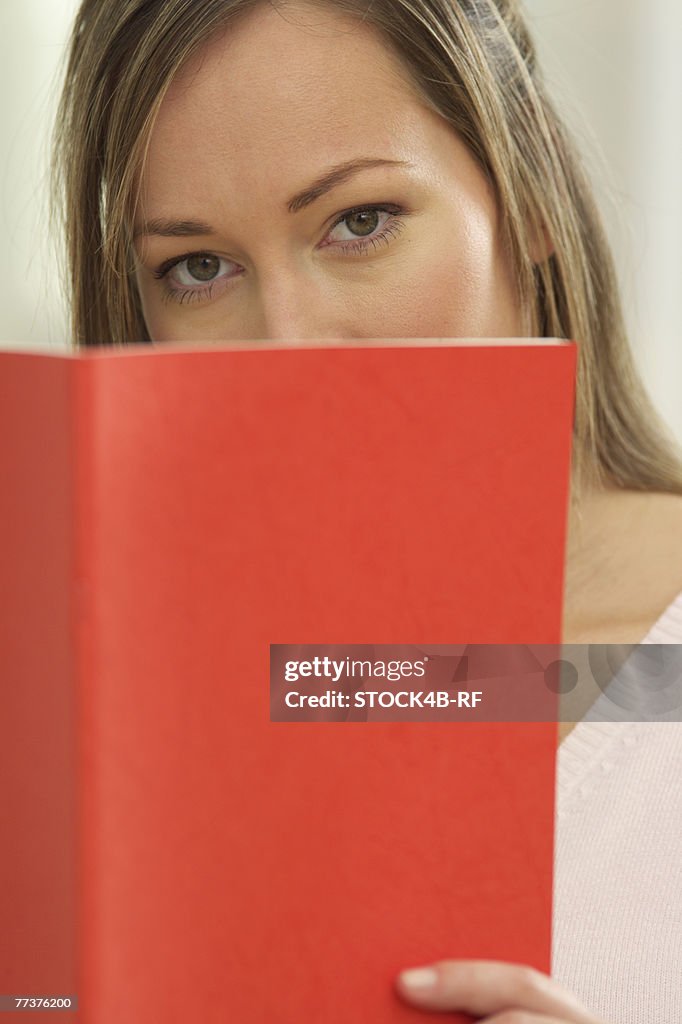 A woman is looking behind a book
