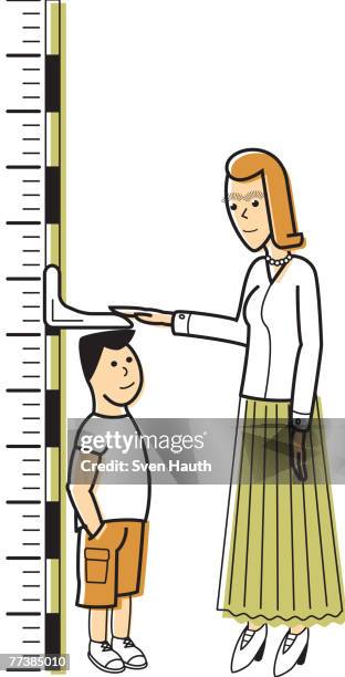 a woman measuring a boy against a growth chart - height chart stock-grafiken, -clipart, -cartoons und -symbole