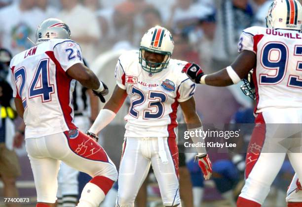 Miami Dolphins defensive back Patrick Surtain of the AFC celebrates with Ty Law of the New England Patriots and Adewale Ogunleye of the Miami...