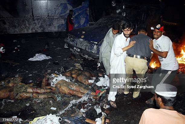 Volunteers remove bodies lying in the street after a powerful suicide car bomb blast was detonated near a vehicle carrying former Pakistani Prime...