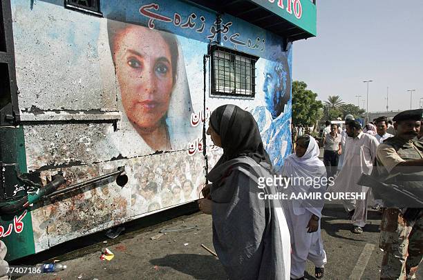 Pakistani onlookers gather beside the damaged vehicle which was carrying former Pakistani prime minister Benazir Bhutto when a suicide attack killed...