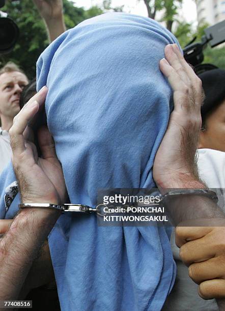 Christopher Paul Neil suspected Canadian paedophile, and nicknamed "Vico" by Interpol, is surrounded by Thai policemen as he covers his face with a...