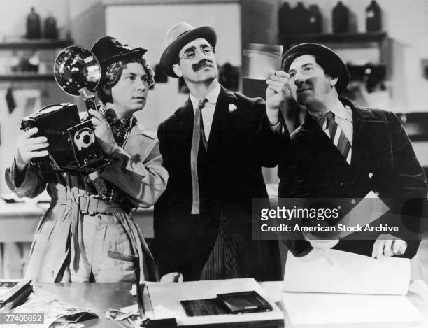 Harpo Marx , Groucho Marx and Chico Marx examining the negatives from a photo-finish in a scene from the comedy 'A Day at the Races', directed by Sam...