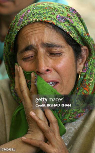 Kashmiri villager weeps as she stands near the body of suspected Hezb-ul-Mujahedeen militant Irhad Ahmed Dar during his funeral procession in...