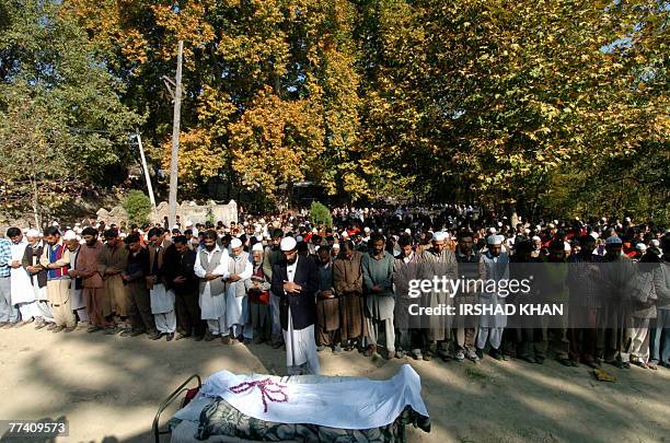 Kashmiri villagers offer prayers as they stand near the body of suspected Hezb-ul-Mujahedeen militant Irhad Ahmed Dar during his funeral procession...