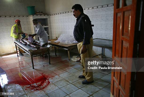 Pakistani policeman looks on as a dead body is washed at the Edhi Morgue October 19, 2007 in Karachi, Pakistan. A suicide bombing killed at least 136...