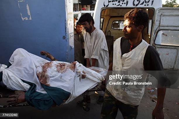 Workers carry another body into the Edhi Morgue October 19, 2007 in Karachi, Pakistan. A suicide bombing killed at least 136 people in an...