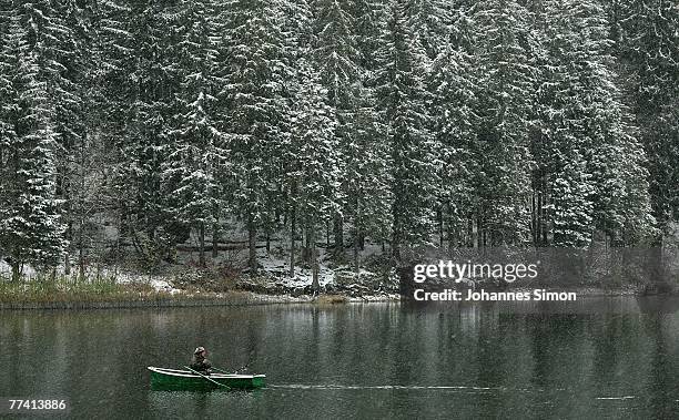 Fisherman crosses the Spitzingsee Lake in a boat during snowfall on October 19, 2007 in Spitzingsee, Germany. Weather forecasts predict more snowfall...
