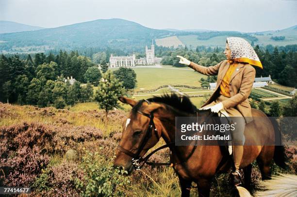 The Queen on horseback looking towards Balmoral Castle, Scotland in the distance during the Royal Family's annual summer holiday in September 1971....