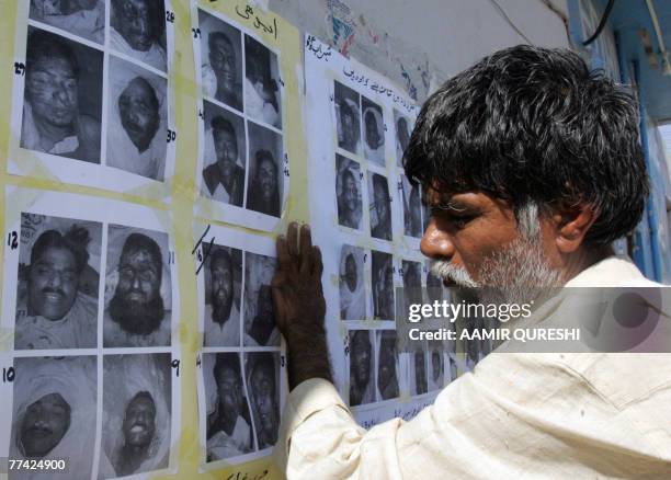 Pakistnai worker of a morgue, run by a private charity Edhi Foundation, pastes photographs of the people who were killed on 18 October in the suicide...