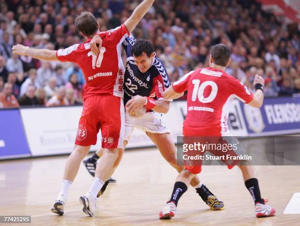 Marcin Lijewski of Flensburg is challenged by Holger Glandorf and Jan Filip of Nordhorn during the Bundesliga Handball game between SG...