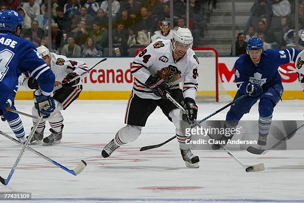 Yanic Perreault of the Chicago Black Hawks skates up ice with the puck followed by Matt Stajan of the Toronto Maple Leafs in a game at the Air Canada...