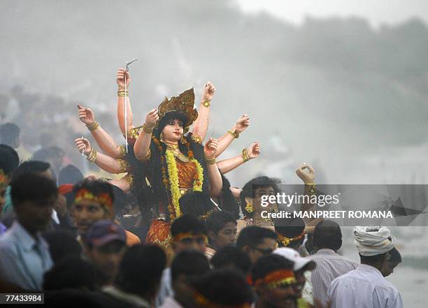Indian Hindu devotees carry an idol of the Goddess Durga into the River Yamuna for immersion in New Delhi, 21 October 2007, on the final day of the...