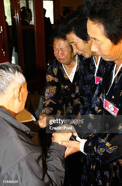 North Korean women cry as they hold the hands of their South Korean brother and father Ryu Hyung-Ryul during their final meeting at the three-day...