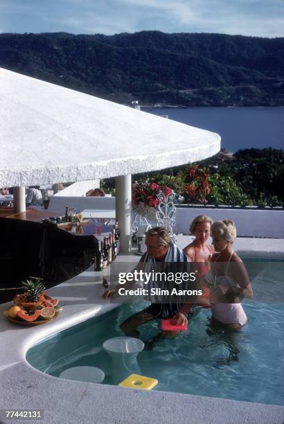 Swiss bandleader and restaurateur Teddy Stauffer with Dorothy Webb and Mrs Charles Rogers in the pool at the Villa Vera Spa & Racquet Club pool,...