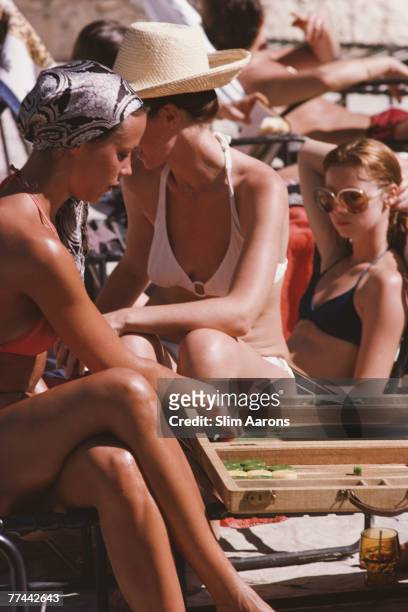 Women playing backgammon while sunbathing at the Habitation Leclerc pool in Haiti, January 1975.